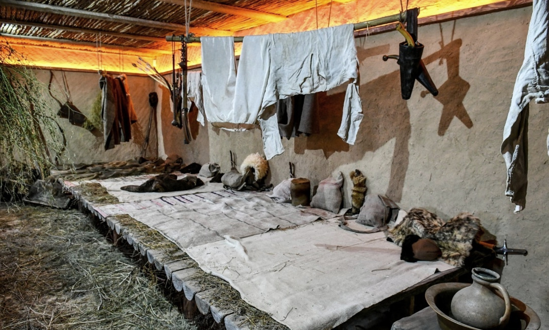 Wooden Cossack hut with benches, a fire and weapons